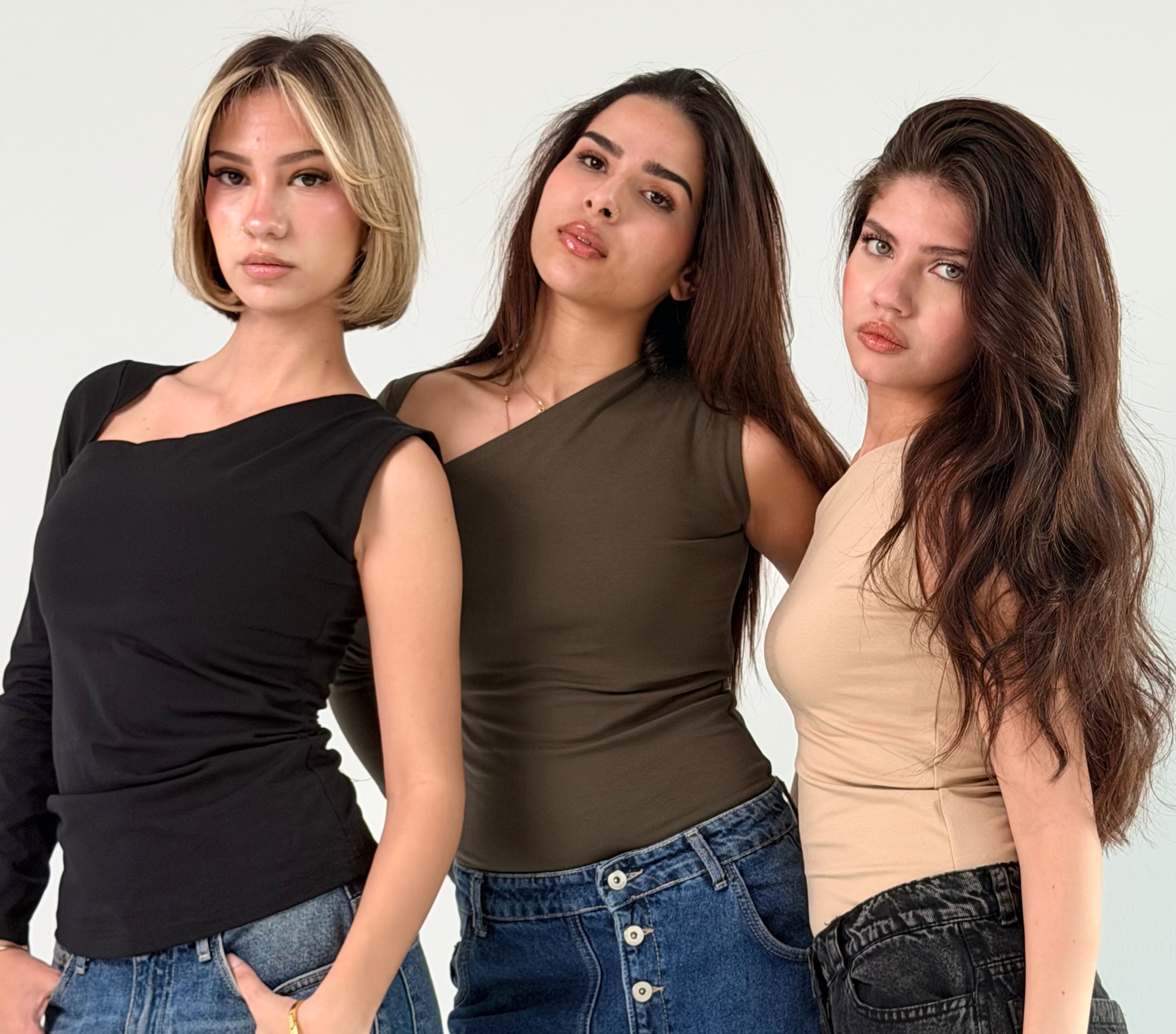 Three women posing together against a plain background